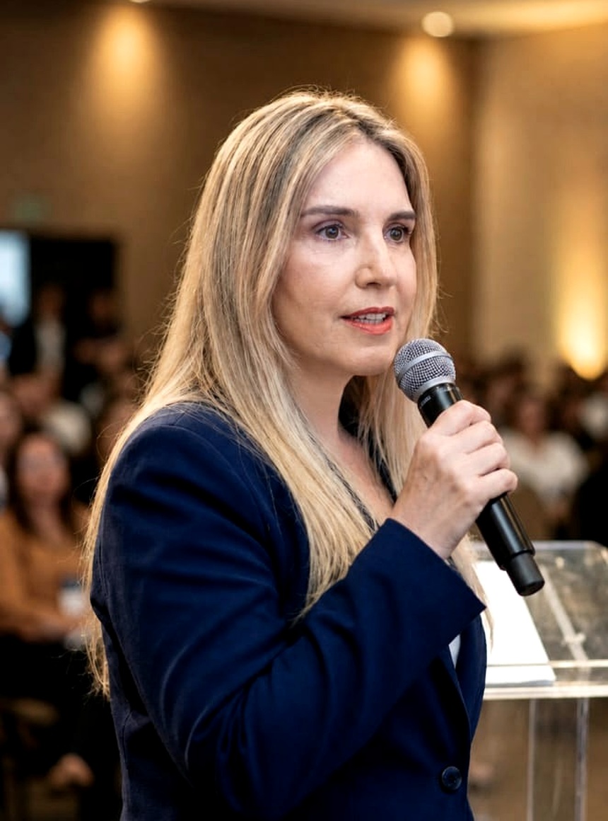 Andréa Boggio sorrindo com microfone em evento