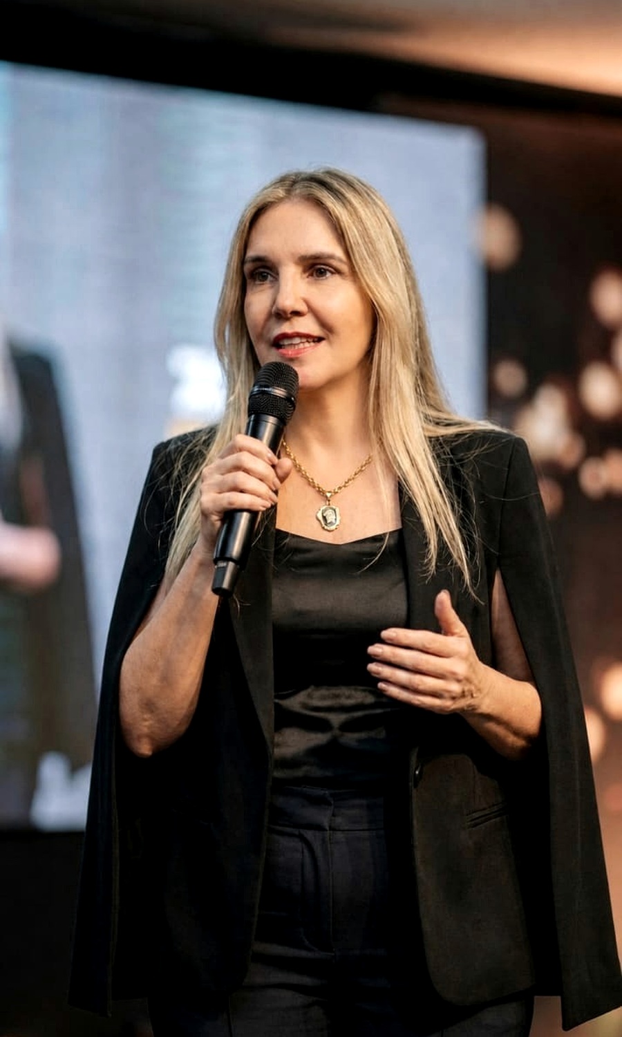 Andréa Boggio em palestra com microfone no palco